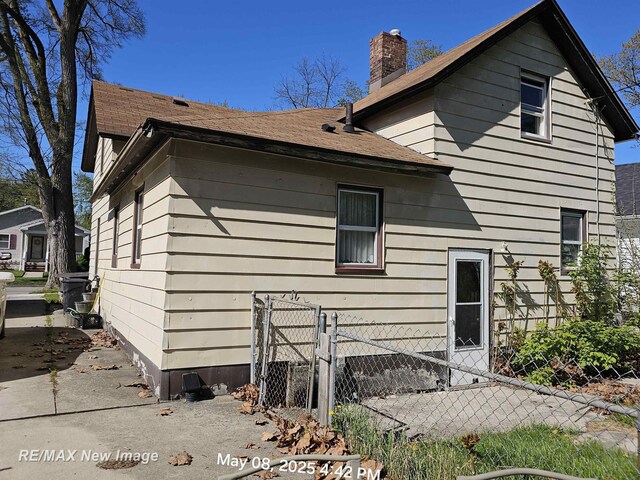 1551 Division St, Saginaw, MI 48602 - view of home's exterior with a chimney and fence