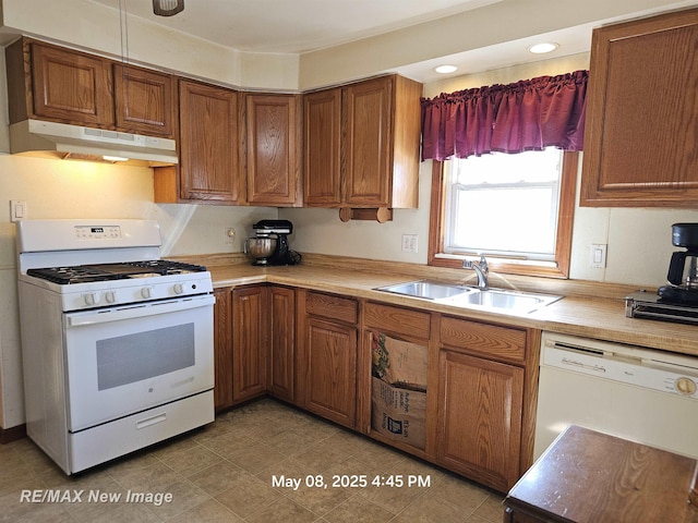 1551 Division St, Saginaw, MI 48602 - kitchen featuring white appliances, under cabinet range hood, a sink, brown cabinetry, and light countertops