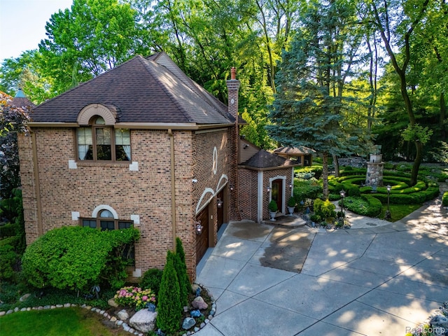 7310 Sandy Creek Ln, Bloomfield Hills, MI 48301 - view of side of property featuring a chimney, brick siding, driveway, and a shingled roof