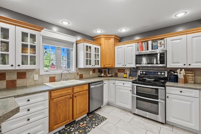 15974 Rustic Ln S, Vicksburg, MI 49097 - kitchen with appliances with stainless steel finishes, a sink, decorative backsplash, light tile patterned floors, and glass insert cabinets