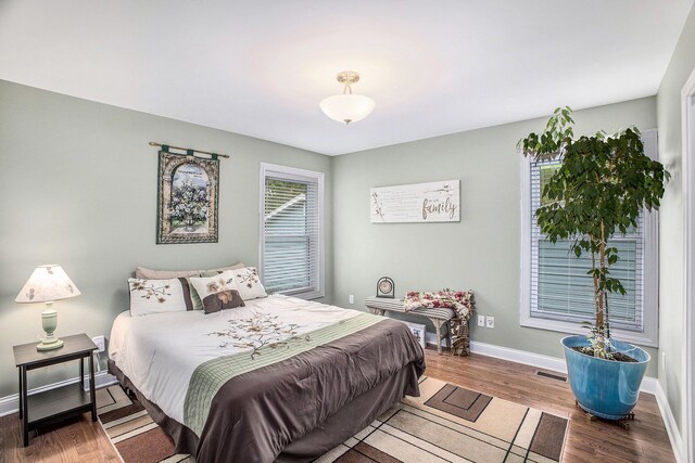 bedroom featuring multiple windows, baseboards, and wood finished floors