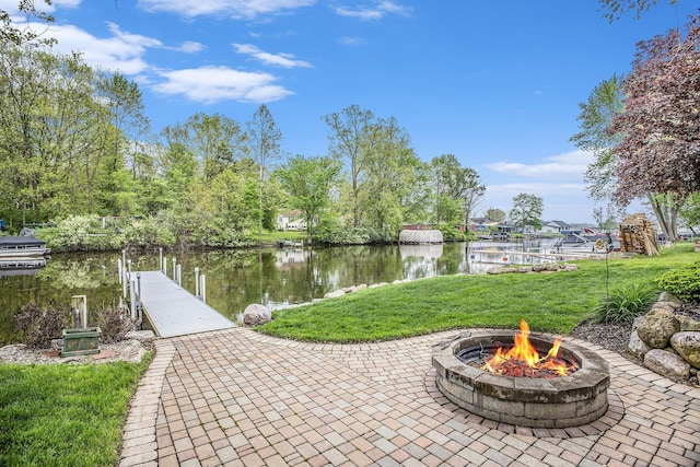 view of patio / terrace with an outdoor fire pit, a boat dock, and a water view
