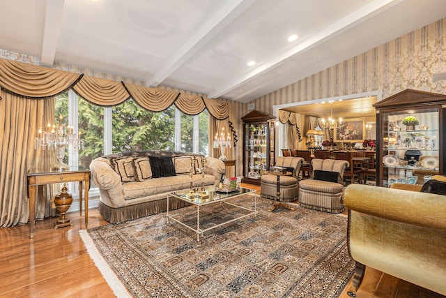 living area featuring wallpapered walls, a chandelier, wood finished floors, and beam ceiling