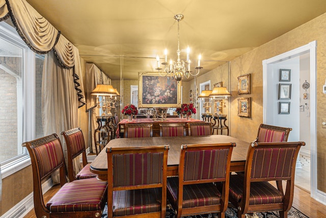 dining area with a chandelier, wood finished floors, and baseboards