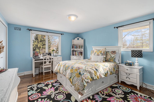 bedroom featuring wood finished floors, multiple windows, baseboards, and an office area