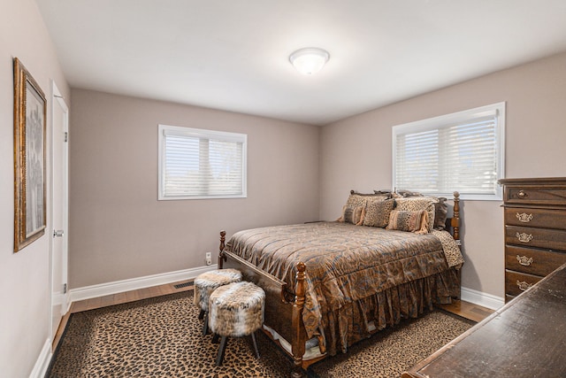 bedroom featuring multiple windows, baseboards, and wood finished floors