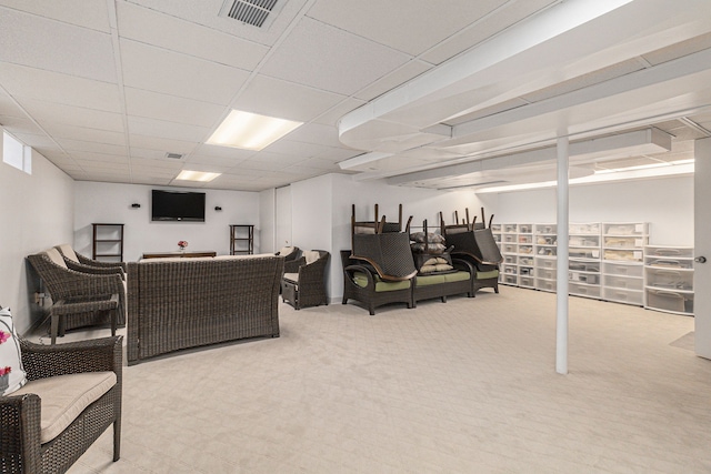 carpeted living area with a paneled ceiling