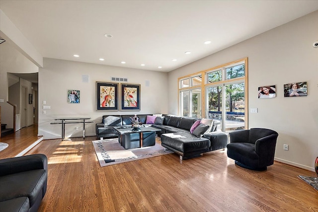 living area with wood finished floors, baseboards, recessed lighting, and stairs
