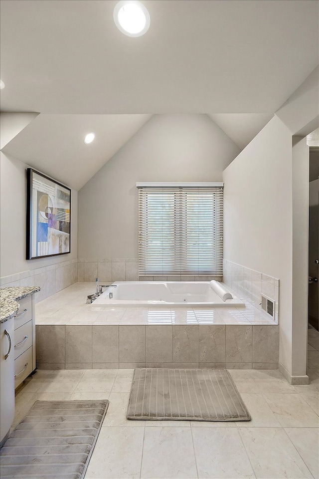 bathroom featuring vaulted ceiling, a garden tub, tile patterned floors, and vanity