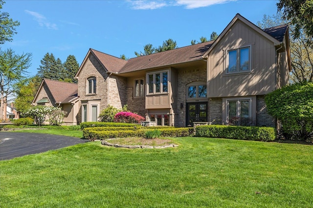 view of front of property with french doors, brick siding, a front yard, and board and batten siding