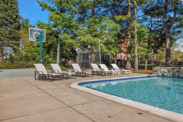 view of pool with fence, view of wooded area, and a patio area
