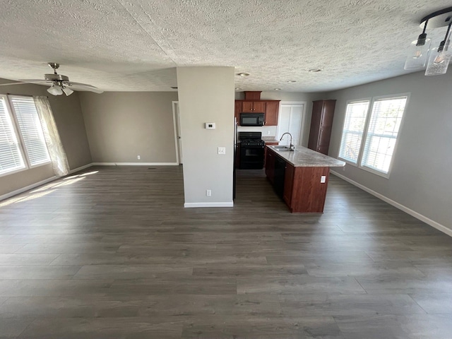 kitchen featuring black appliances, open floor plan, baseboards, a sink, and a textured ceiling