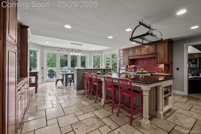 4906 Charing Cross Rd, Bloomfield Hills, MI 48304 - kitchen with recessed lighting, stone tile flooring, dark countertops, tasteful backsplash, and a kitchen bar