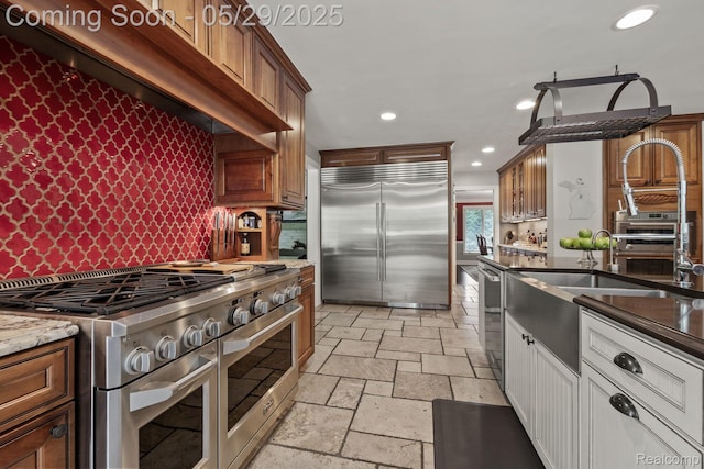 4906 Charing Cross Rd, Bloomfield Hills, MI 48304 - kitchen with premium appliances, stone tile floors, recessed lighting, dark stone counters, and backsplash