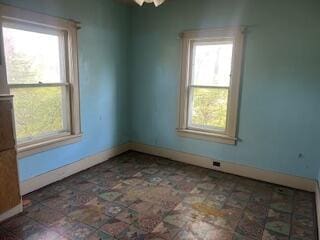unfurnished room with healthy amount of natural light and baseboards