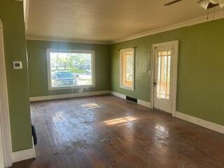 empty room with baseboards, ornamental molding, a ceiling fan, and wood finished floors