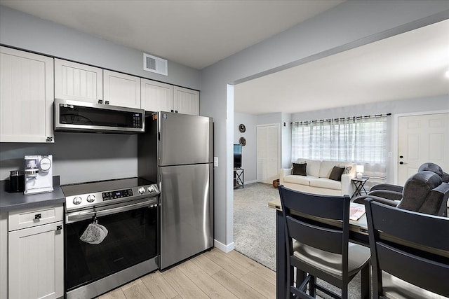 16046 Holz Dr Unit 48, Southgate, MI 48195 - kitchen with appliances with stainless steel finishes, white cabinets, open floor plan, light wood finished floors, and dark countertops