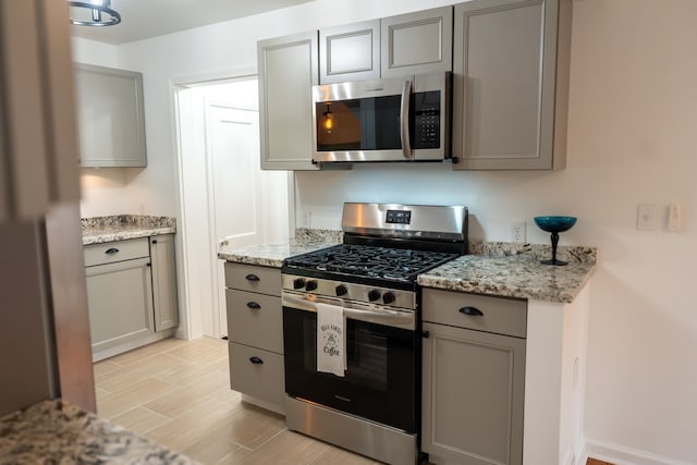 13185 Sycamore St, Southgate, MI 48195 - kitchen with appliances with stainless steel finishes, gray cabinets, light wood-style floors, and light stone counters