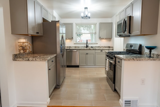 13185 Sycamore St, Southgate, MI 48195 - kitchen with stainless steel appliances, a sink, a chandelier, wood tiled floors, and light stone counters