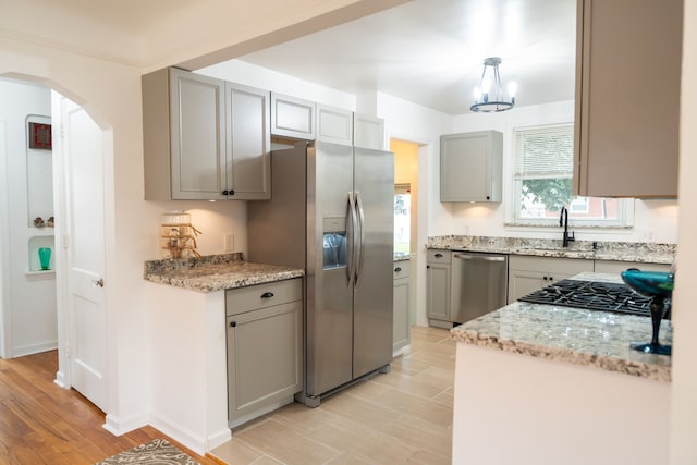 13185 Sycamore St, Southgate, MI 48195 - kitchen with appliances with stainless steel finishes, a sink, gray cabinetry, arched walkways, and light wood-style flooring