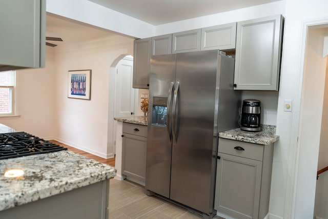 13185 Sycamore St, Southgate, MI 48195 - kitchen with stainless steel refrigerator with ice dispenser, gray cabinetry, arched walkways, and light stone counters