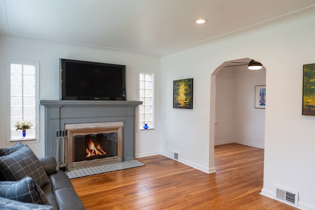 13185 Sycamore St, Southgate, MI 48195 - living area featuring arched walkways, wood finished floors, a glass covered fireplace, baseboards, and recessed lighting