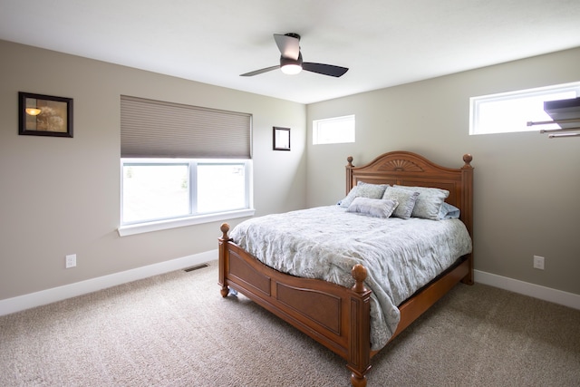 bedroom featuring light colored carpet, baseboards, and a ceiling fan