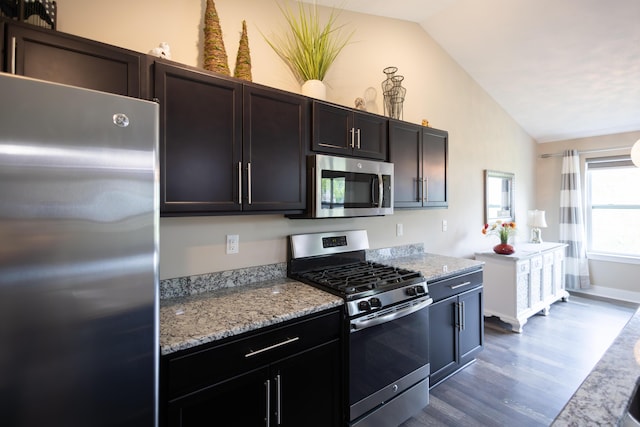 kitchen featuring stainless steel appliances, vaulted ceiling, dark wood-style floors, and light stone countertops