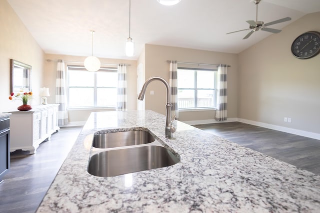 kitchen with lofted ceiling, a sink, dark wood-style floors, ceiling fan, and light stone counters