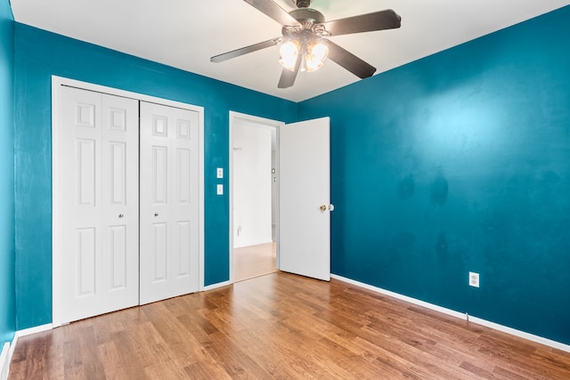 unfurnished bedroom with wood finished floors, a closet, ceiling fan, and baseboards