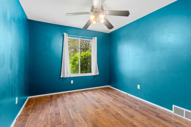 spare room with wood finished floors, ceiling fan, and baseboards