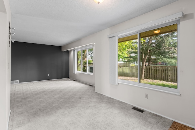 unfurnished room featuring carpet flooring, baseboards, and a textured ceiling