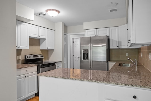 kitchen featuring stainless steel appliances, a sink, stone countertops, a peninsula, and backsplash