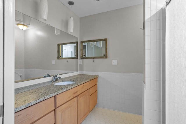 full bath with tile walls, tile patterned flooring, wainscoting, and vanity