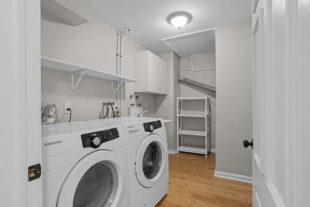 clothes washing area featuring independent washer and dryer, cabinet space, light wood finished floors, and baseboards
