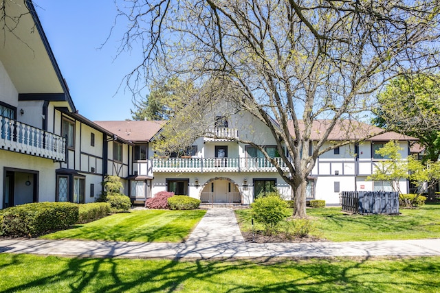 view of front of property with stucco siding, a front lawn, and a balcony