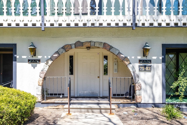 view of exterior entry featuring a gate and stucco siding