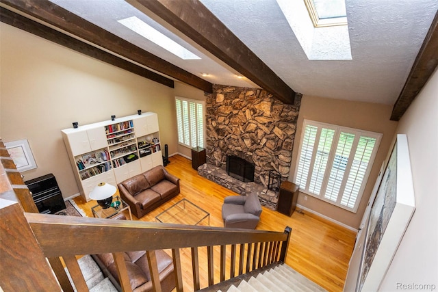 5423 Hauser Way W, Bloomfield, MI 48323 - living room with a fireplace, wood finished floors, a skylight, healthy amount of natural light, and a textured ceiling