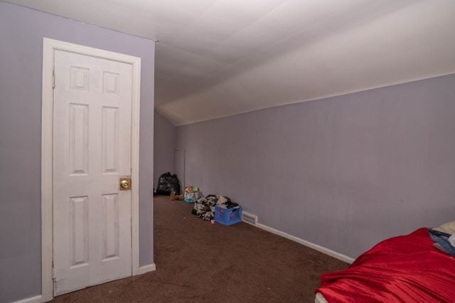 unfurnished bedroom featuring lofted ceiling, carpet flooring, and baseboards