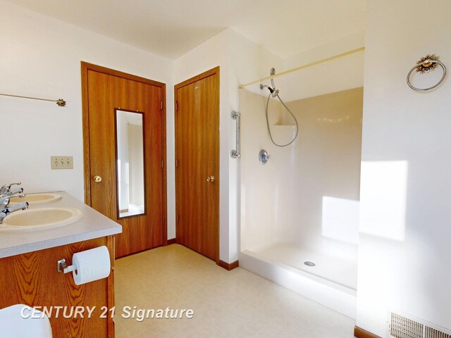 5530 Hess Rd, Saginaw, MI 48601 - bathroom with a shower, tile patterned floors, double vanity, and baseboards
