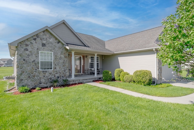 ranch-style home featuring covered porch, stone siding, a front yard, a garage, and roof with shingles