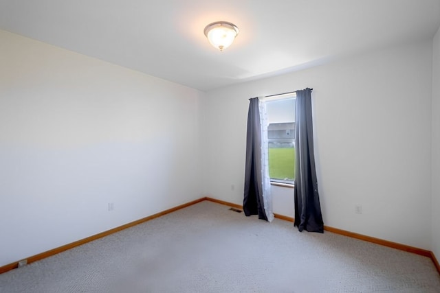 empty room featuring baseboards and light colored carpet