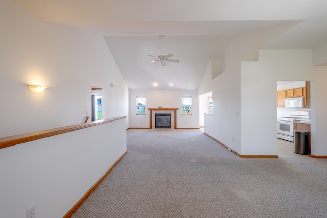 unfurnished living room featuring high vaulted ceiling, baseboards, light carpet, a tiled fireplace, and a ceiling fan