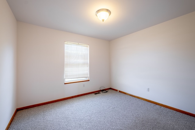 spare room featuring carpet and baseboards