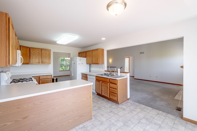 kitchen featuring white appliances, a peninsula, a sink, light countertops, and baseboards