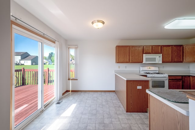 kitchen featuring white appliances, brown cabinets, light countertops, and baseboards