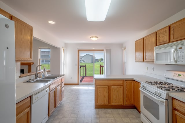 kitchen with white appliances, a sink, a peninsula, light countertops, and recessed lighting