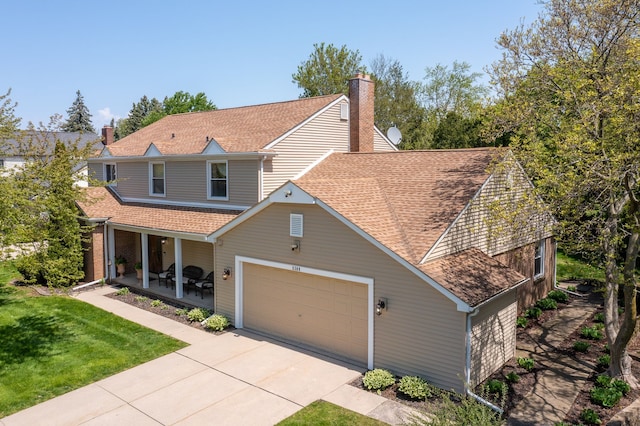 traditional-style home featuring covered porch, an attached garage, a shingled roof, driveway, and a front yard