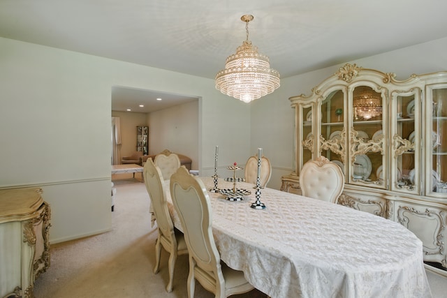 dining space featuring light carpet and a chandelier