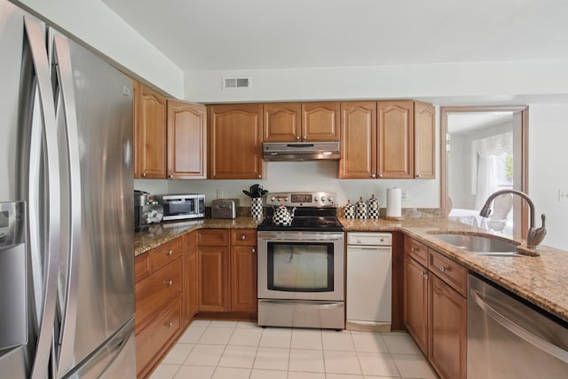 kitchen featuring appliances with stainless steel finishes, a sink, under cabinet range hood, and stone counters